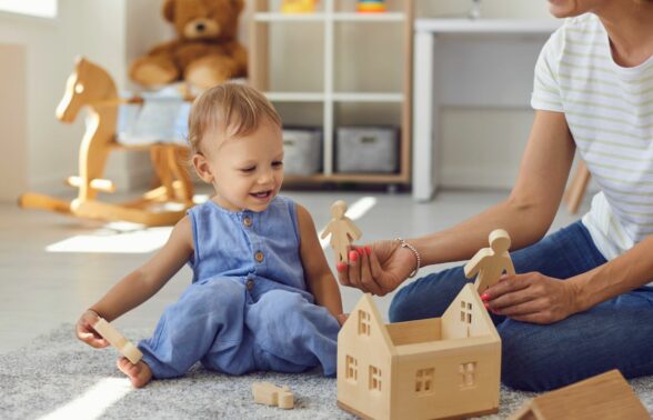 Jeune enfant qui joue avec un adulte assis par terre.