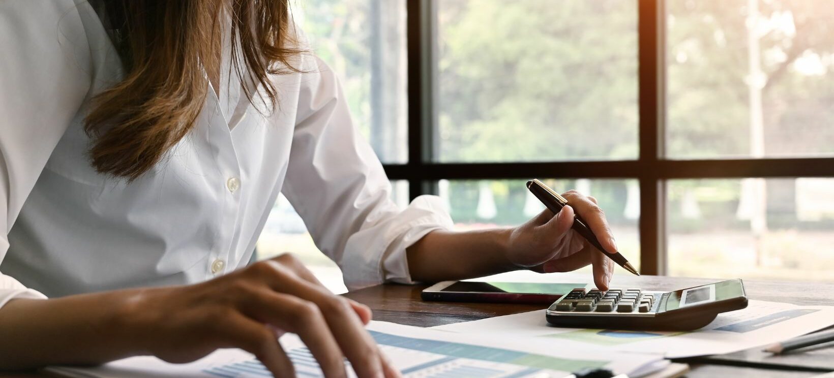 Jeune femme qui réalise ses comptes avec une calculatrice