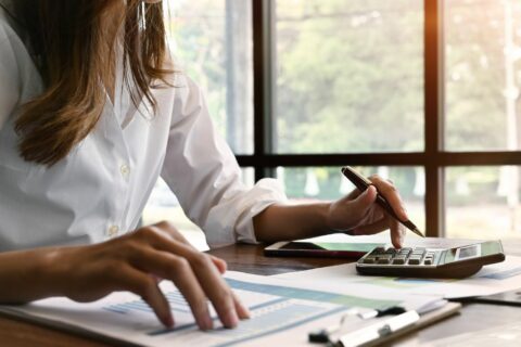 Jeune femme qui réalise ses comptes avec une calculatrice