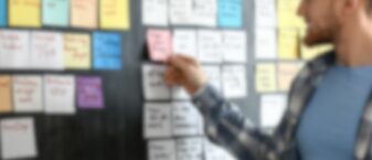 Jeune qui recherche un job en consultant des post-it.